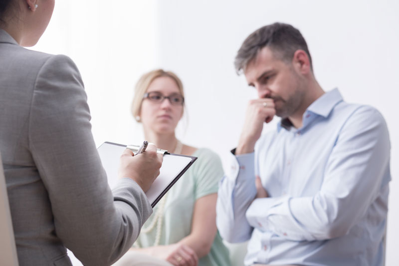Frustrated couple talking to a woman who is writing on a clipboard
